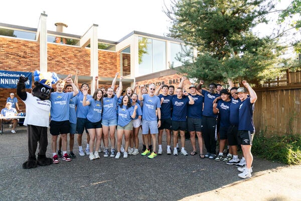Students wearing blue shirts line up with a mascot Bruin. 