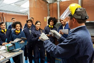 Group of college students in an engineering class looking at the instructor and paying attention.