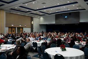 Faculty and staff at DePaul University listen to a speaker in a large conference room.