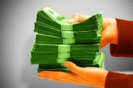 A photo illustration of hands holding a stack of money.