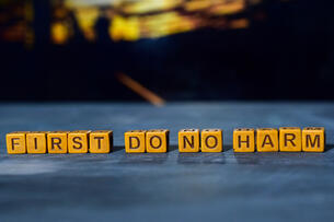 The words "First do no harm," spelled out in wooden blocks.