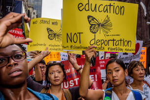A group of Dreamers hold signs. A yellow sign reads "education not deportation." 