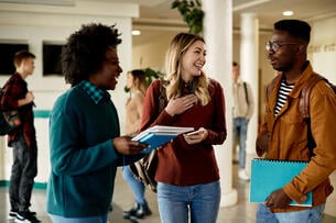 Happy students having fun while communicating at university hallway.