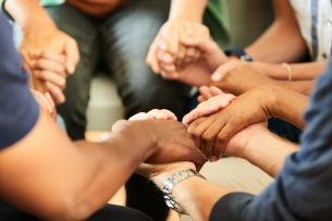 A group of people hold hands sitting in a circle