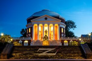 The Rotunda, designed by Thomas Jefferson, on the University of Virginia campus, lit from within in a photograph taken at dusk.