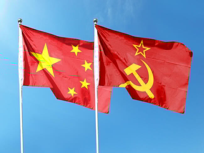 A photo of the flags of the People's Republic of China and the Soviet Union waving in the wind against a blue-sky background.