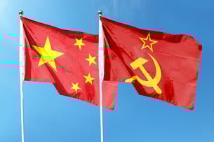 A photo of the flags of the People's Republic of China and the Soviet Union waving in the wind against a blue-sky background.