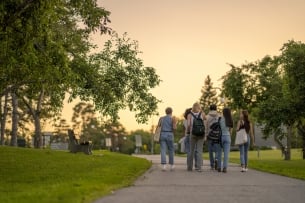 A group of university students are seen from behind walking outside on campus as they make their way to class.