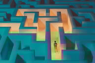 An illustration of a woman standing at the start of an illuminated pathway within a dark maze.