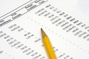 A photo of a budget spreadsheet with a pencil lying on top.
