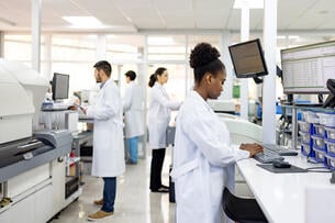 A group of four scientists of different races and genders work in a research laboratory.