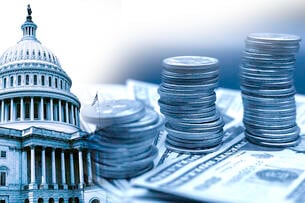 A blue-scale image of the U.S. Capitol building with stacks of U.S. currency—both dollars and coins—stacked in the foreground of the picture.