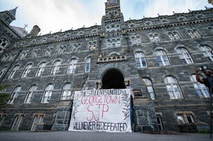 Students with sign outside building 