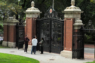 The Van Wickle gates at the entrance to Brown University with 3 people standing in front.