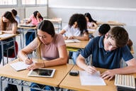 Students at their desks writing in a classroom. 
