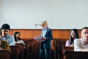 A professor interacts with engaged students in a university lecture hall, fostering a supportive and educational atmosphere.
