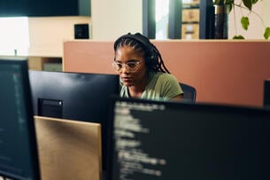 Focused female programmer working on code in modern office
