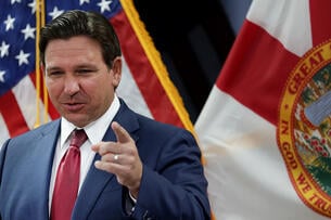 Florida governor Ron DeSantis speaking in front of a flag