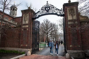 Students walk through a gate on Harvard's campus. 