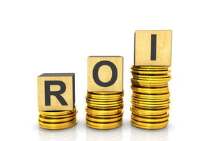Three wooden alphabet blocks that together spell "ROI" sit atop three stacks of gold coins.