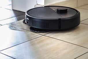 A robot vacuum cleaner on what appears to be a kitchen floor.