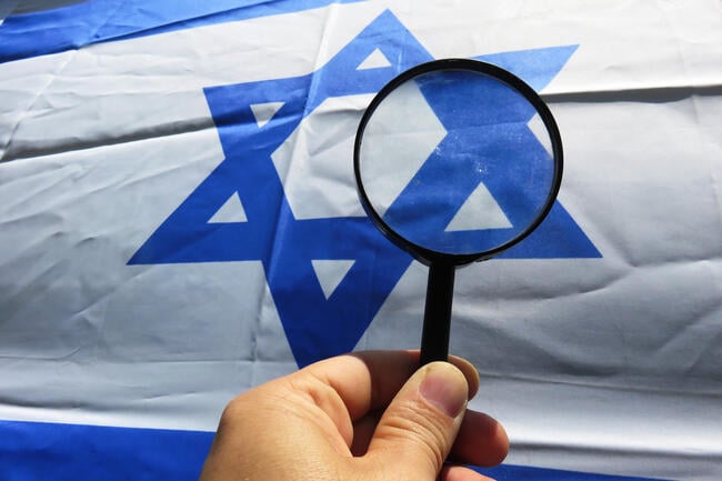 A photo of a hand holding a magnifying glass over an Israeli flag.