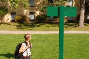 A college student looks at a sign for direction.