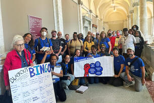 A group of AFT Local 2026 members hold up signs. 