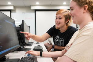 Two students work together at Champlain College at a computer lab