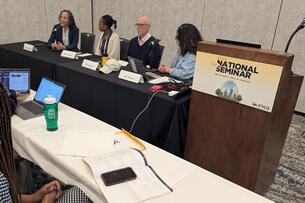 Four panelists sit at a table next to a lectern with the Education Writers Association logo on it.
