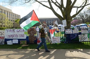 A protester holding a Palestinian flag walks past a pro-Palestinian camp outside of Northwestern University.