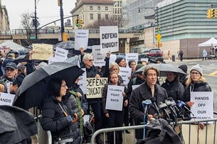 Columbia professors wear black and hold signs with black lettering on white paper