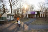 Mother walking toward a childcare center with two children in the early morning on a college campus.