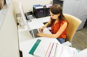 A young woman works at a desk in an office space