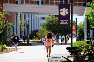A student wearing a backpack walks on Clemson University's campus