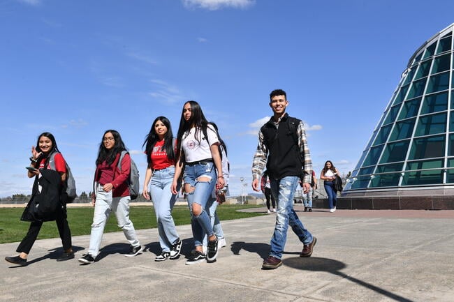 A group of students walk beside a large building.