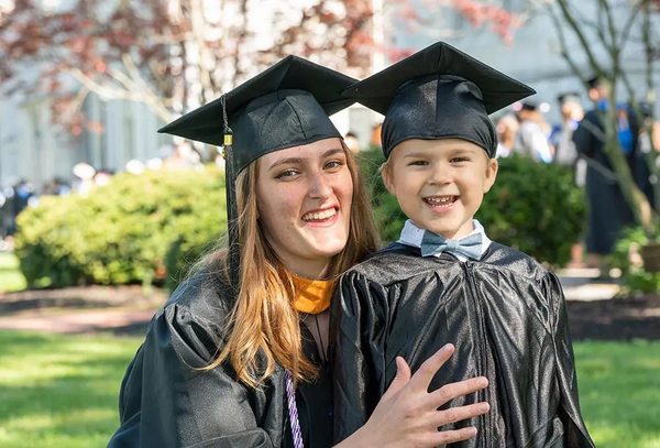 A Wilson student and her son smile for a photo at Wilson College’s graduation ceremony, both wearing a black cap and gown