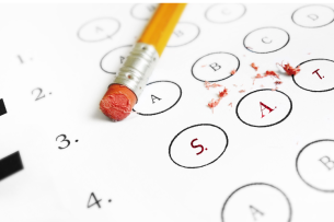 A No. 2 pencil with a well-worn eraser lies atop a standardized test form with multiple-choice bubbles. The three bubbles in the foreground of the picture read “SAT.”
